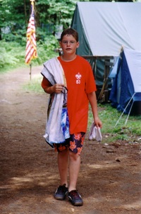 A scout wearing a red Troop 53 class B tee-shirt and wearing a baithing suit looking at the camera.