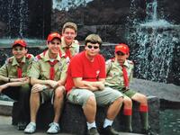 Five scouts sitting in front of a water fall fountain.