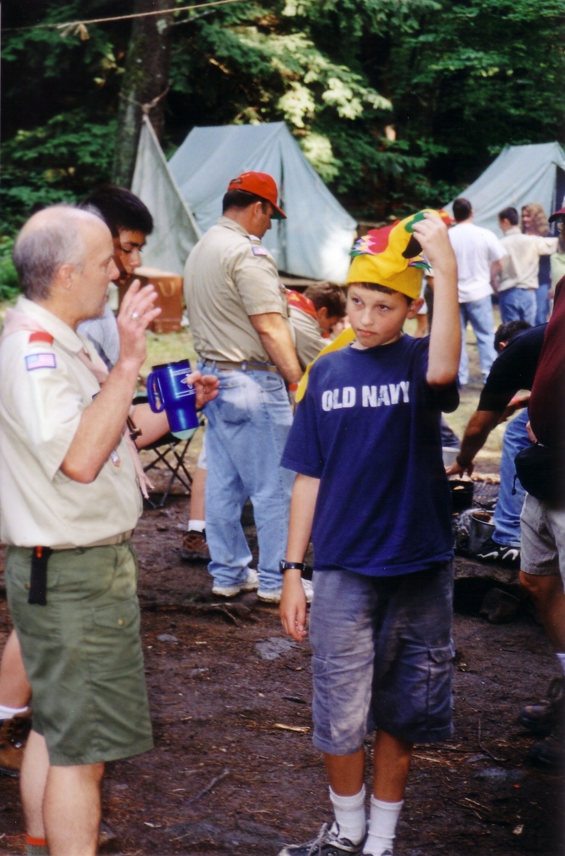 Scoutmaster McKnight talking to Seth Hendrick, who is wearing a colorful felt parrot hat.
