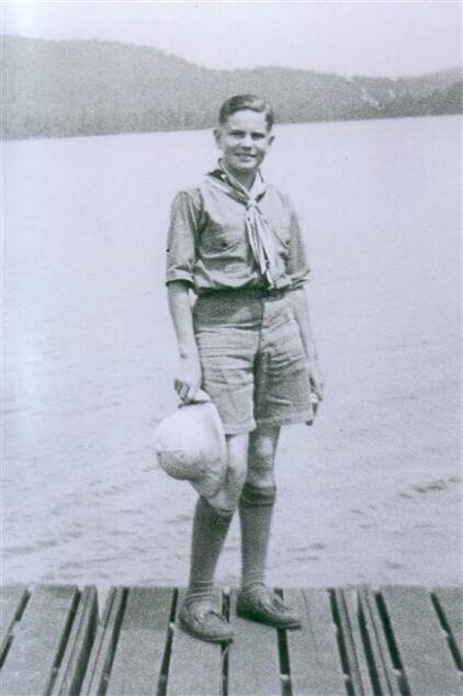 A scout standing on a dock in uniform, facing the camera.