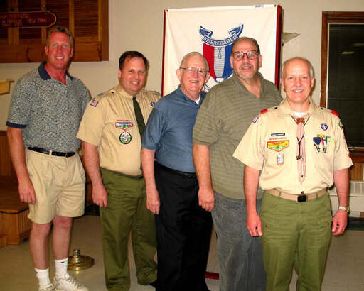Five men smiling for the camera in front of an Eagle Scout banner.