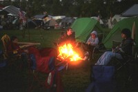 Four scouts sitting around the campfire as night falls.