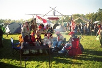 A group of scouts sitting around a campfire.  Many of whom are in class A uniforms.