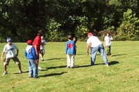 Scouts and an adult playing football in a field.