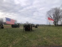 The American flag flies to the left, and the troop flag flies to the right.  There is a wreath rack in between the two.