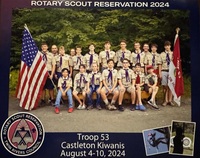 19 people in Class A uniforms smiling for the camera.  To the left is the American flag, and to the right is the Troop flag.  There is text above and below the photo that reads 