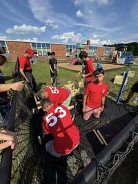 Scouts are assembling the garden boxes on a black tarp.