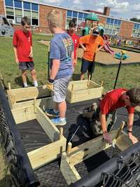 Scouts moving the flower boxes onto a black tarp.