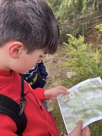 A scout looking at a map with a compass in the lower-left corner of the map.
