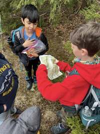 A scout looks at a map with a compass with another scout.