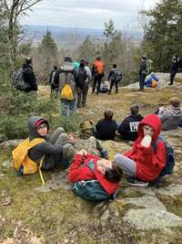 Three scouts look at the camera while behind them is the cliffs at Rotary.  A group of others looks over the cliff.