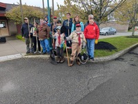 Scouts and Scouters stand on a curb holding shovels and smiling for the camera.