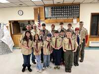 Sixteen scouts and adults wearing class A uniforms smiling at the camera.
