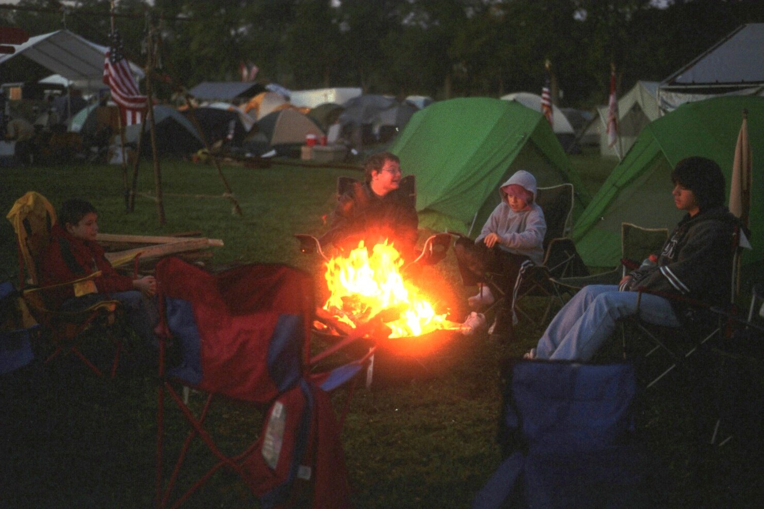 Four scouts sitting around the campfire as night falls.