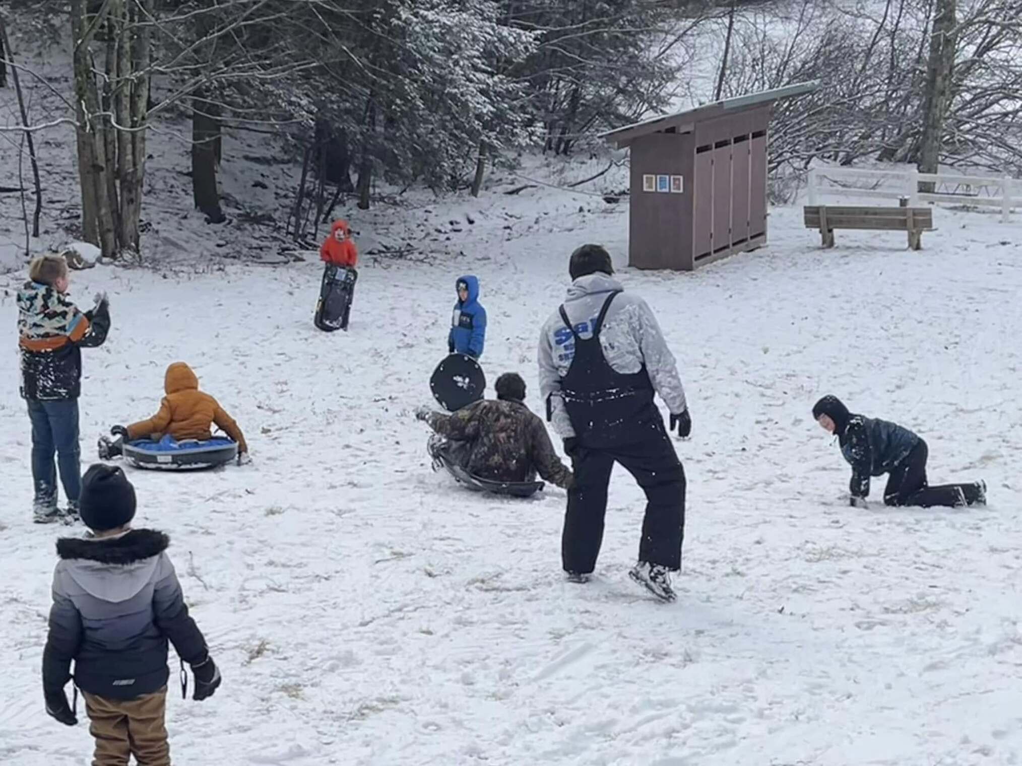 Eight scouts sledding down a hill.
