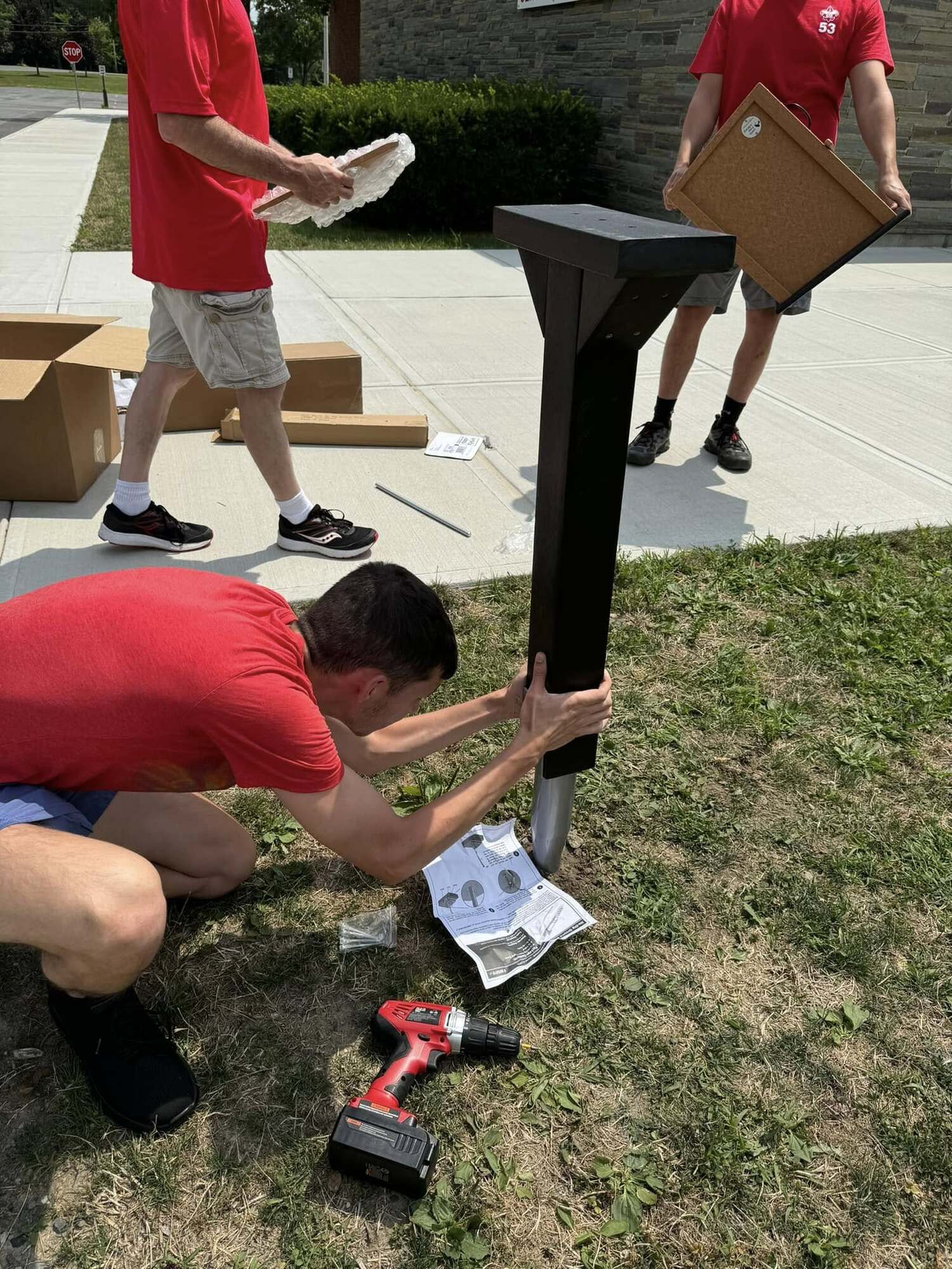 One person is knelt down trying to put the post on the stake in the ground.