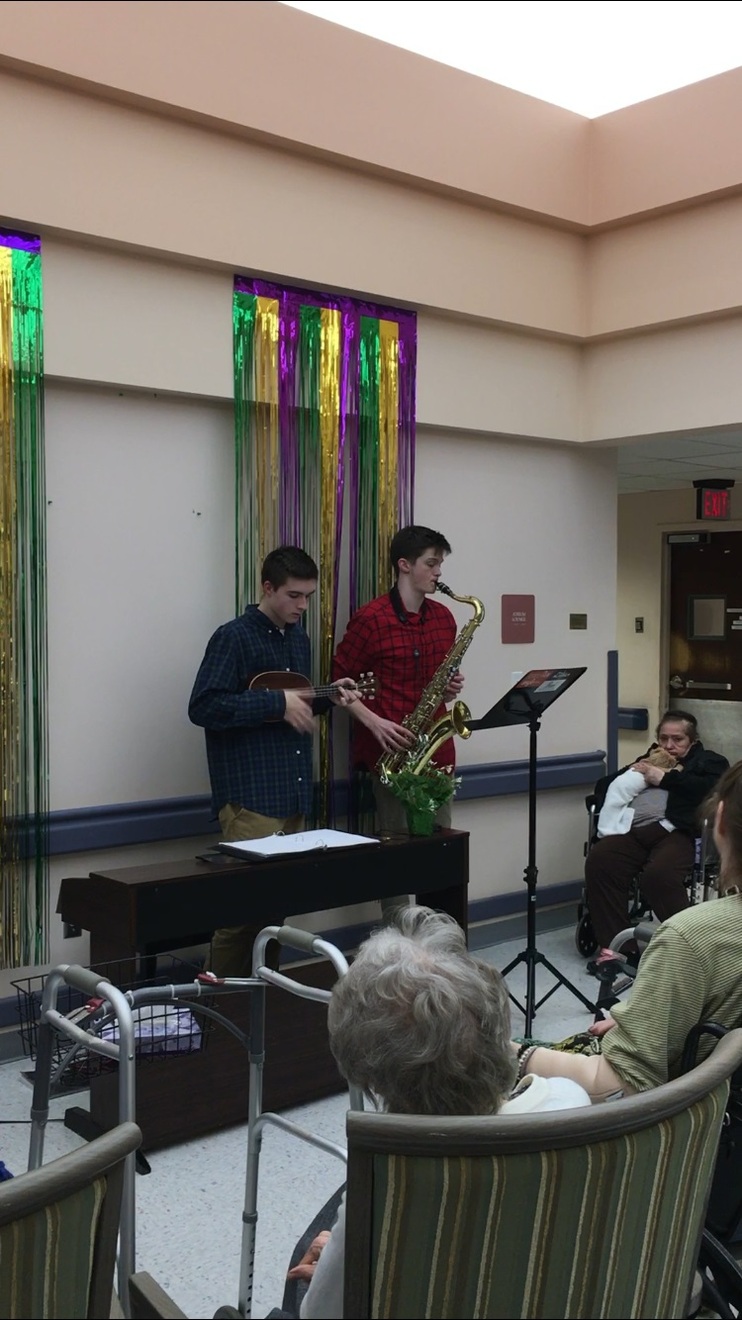 A student on the left playing the ukulele, and a student on the right playing the Saxophone.