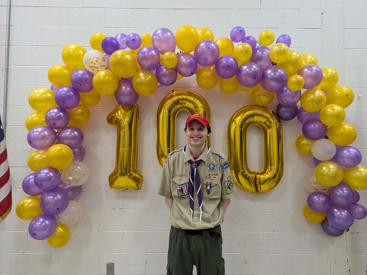 A man in a class A uniform standing in front of the balloon wall.