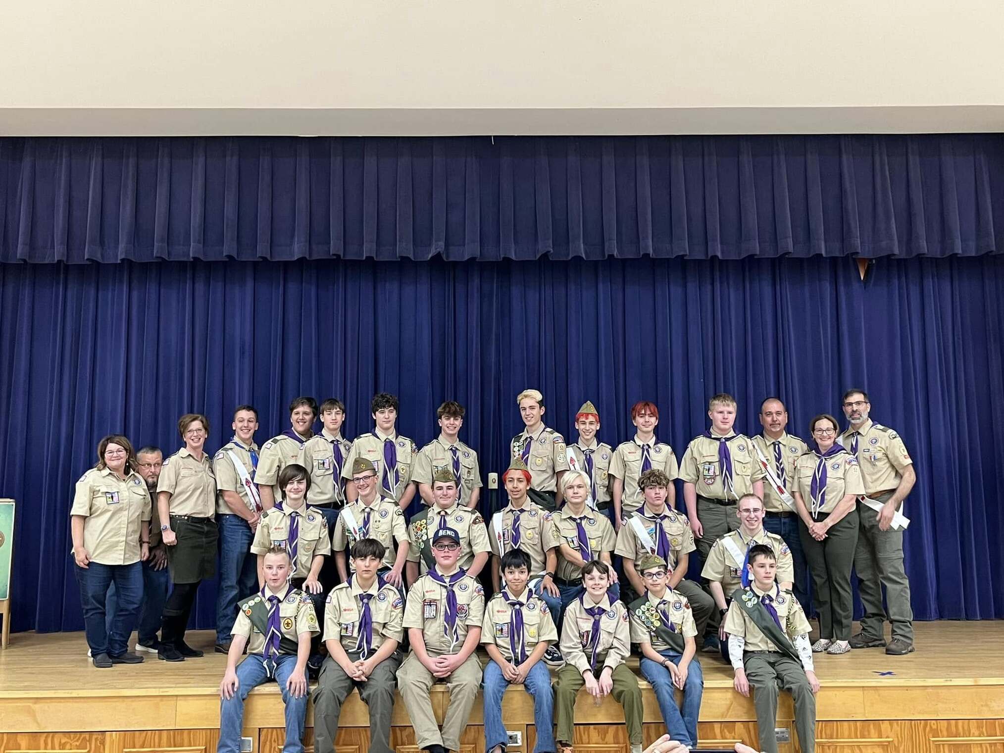 29 people wearing class A uniforms on a stage.